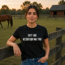 Woman wearing black "They Are Astroturfing You" graphic t-shirt outdoors