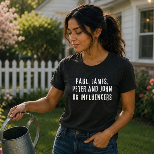 Woman wearing black "Paul, James, Peter and John OG Influencers" graphic t-shirt outdoors